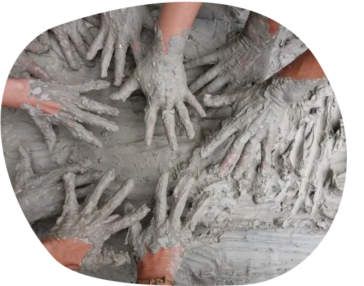 Mani di più persone sporche di argilla grigia durante un laboratorio creativo