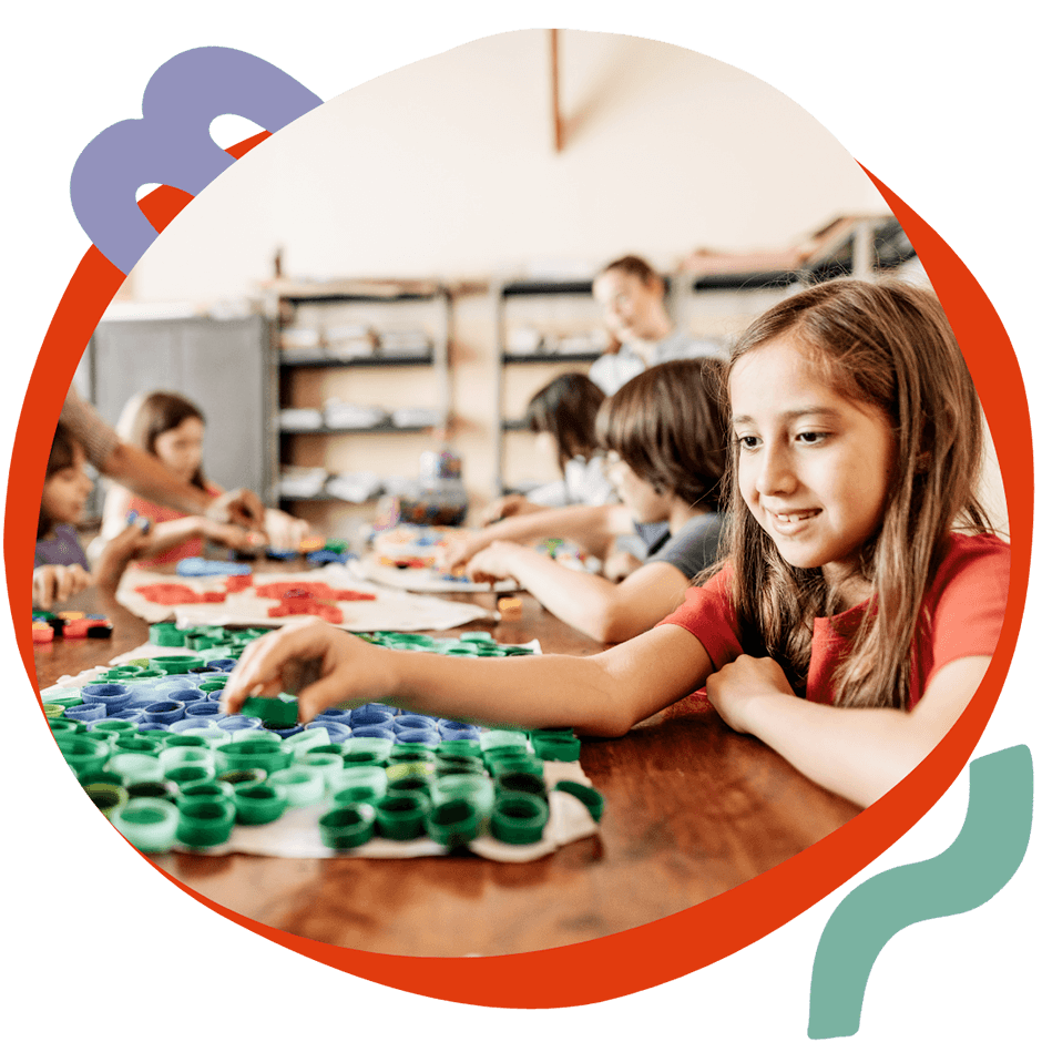 Una bambina sorridente che lavora a un laboratorio creativo con materiali colorati, durante un'attività Artlish del corso estivo Move Your Summer