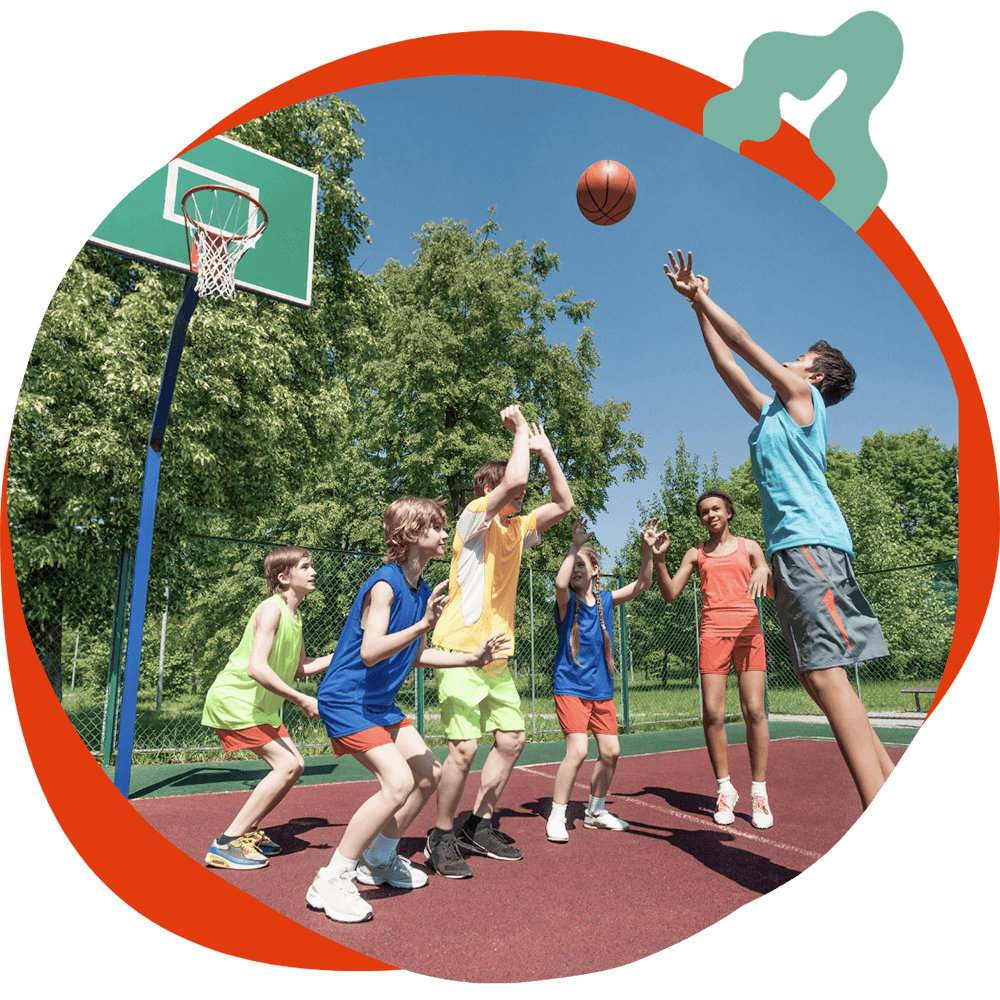 Un gruppo di ragazzi che gioca a basket all'aperto in una giornata di sole, durante un'attività sportiva del corso estivo Move Your Summer