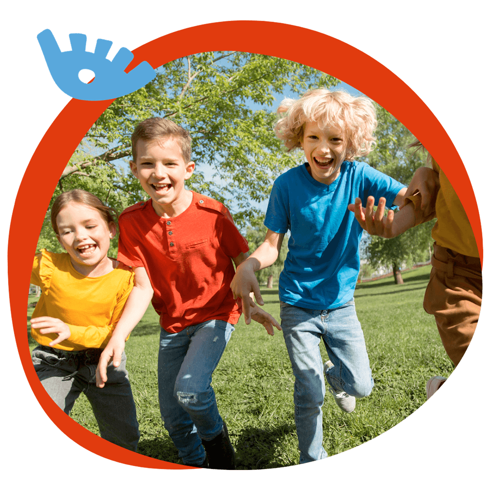 Tre bambini che corrono e ridono in un parco verde durante un'attività all'aperto del corso estivo Move Your Summer