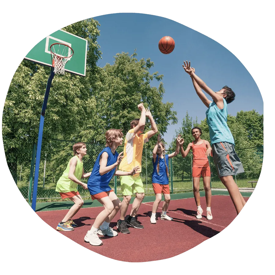 Un gruppo di ragazzi che gioca a basket all'aperto in una giornata di sole, durante un'attività sportiva del corso estivo Move Your Summer